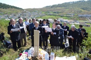 墓標の前で墓参の報告をする龍山墓参団（左端が藤川さん）